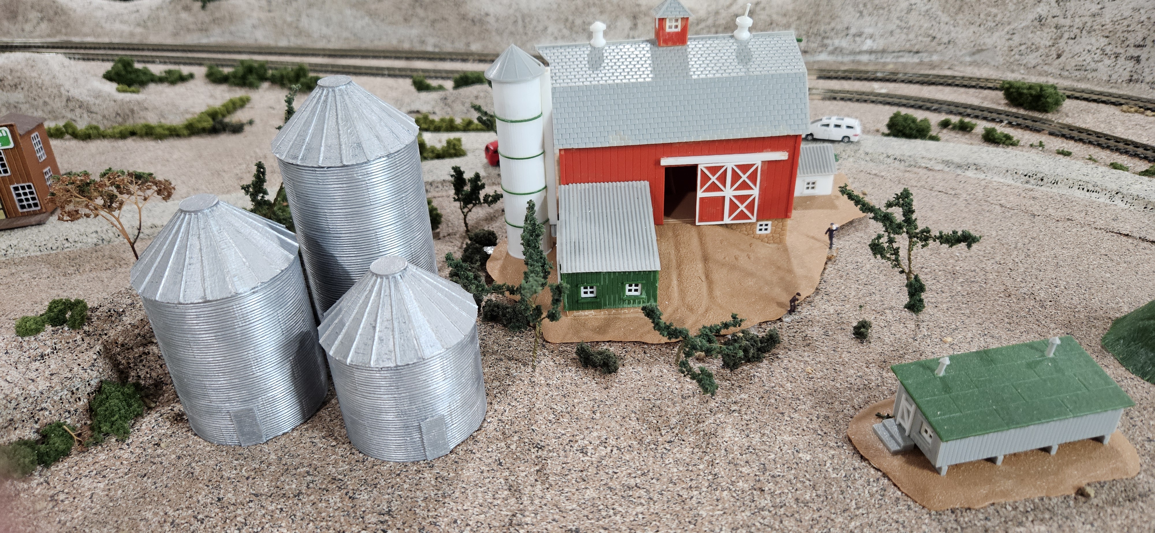 Three painted N scale grain silos installed beside a farm scene