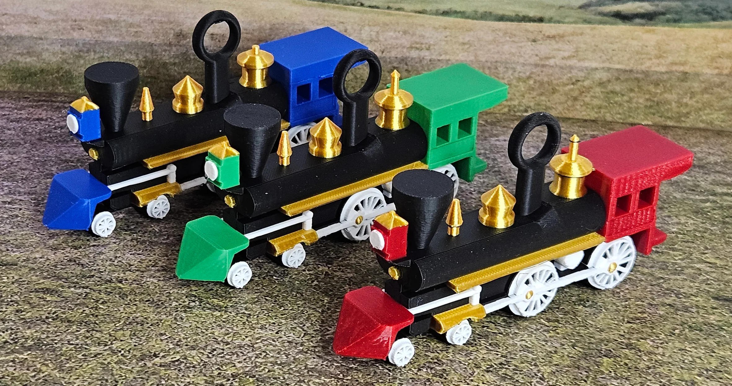 Set of three steam locomotive Christmas ornaments in blue, green, and red
